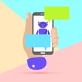 hand holding mobile phone with chat robot bot message notifications on pastel colored blue and pink background. Arm with