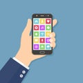 Hand holding mobile phone with colorful application icons on the screen. Flat design concept. Royalty Free Stock Photo