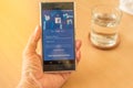 Hand holding mobile phone with Facebook application.