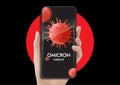 Hand holding mobile phone with omicron COVID 19 variant strain