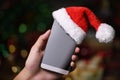 Hand holding mobile phone with Santa Claus ` hat on top on Christmas