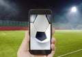 Mobile phone showing football on screen in stadium background Royalty Free Stock Photo