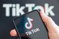 Hand holding a mobile phone with TikTok logo social media computer screen