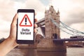 Hand Holding Mobile Phone With With Warning Message Delta Variant And London Tower Bridge