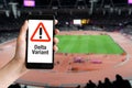 Hand holding mobile phone with with warning message delta variant at stadium Royalty Free Stock Photo