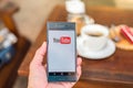 Hand holding mobile phone with Youtube logo in coffee shop. Royalty Free Stock Photo