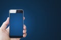 Hand holding mobile smart phone, blank blue screen, on gradient blue background Royalty Free Stock Photo