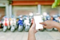 Hand holding mobile smart phone with blurry showroom motorcycle