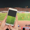 Hand holding mobile smart phone with football stadium screen, bl Royalty Free Stock Photo