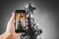 Hand holding mobile smart phone, taking photo of Christmas star on Christmas tree with colorful lights Royalty Free Stock Photo