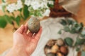 Hand holding modern Easter egg on background of blooming spring flowers on rustic table with basket. Stylish pastel green Easter Royalty Free Stock Photo