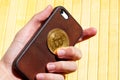 Hand holding a modern smartphone and a golden bitcoin coin symbol. E-commerce, earning with mobile crypto currency trading apps