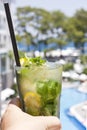 Hand holding Mojito cocktail on the background of the pool Royalty Free Stock Photo