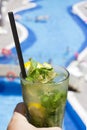 Hand holding Mojito cocktail on the background of the pool Royalty Free Stock Photo
