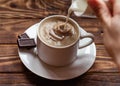 Hand holding mug of milk and pouring it to cap of coffee  on small plate with two small chocolate.   Flat Lay with no people Royalty Free Stock Photo