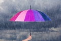 Hand holding multicolored umbrella under dark sky with rain Royalty Free Stock Photo