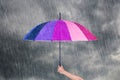 Hand holding multicolored umbrella under dark sky with rain Royalty Free Stock Photo