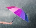 Hand holding multicolored umbrella under dark sky with rain Royalty Free Stock Photo