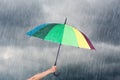 Hand holding multicolored umbrella under dark sky with rain Royalty Free Stock Photo