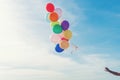 Hand holding multicoloured balloons for relax on tropical beach sunny day, vintage tone. Royalty Free Stock Photo