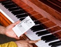 Hand holding music note to play correct key on piano keyboard Royalty Free Stock Photo