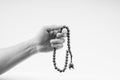 Hand holding a muslim rosary beads or Tasbih on black and white.