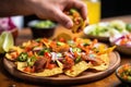 hand holding nacho with a pizza cutter in the background Royalty Free Stock Photo