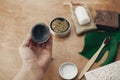 Hand holding natural eco charcoal toothpaste in glass jar on background of bamboo toothbrush, soap, solid shampoo, metal razor, Royalty Free Stock Photo