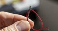 Hand holding needle with red thread closeup Royalty Free Stock Photo
