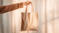 The hand holding a neutral tote bag with a minimalist background. AI generated image Royalty Free Stock Photo