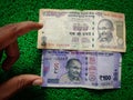 Hand holding of new and old Indian hundred rupees notes.