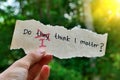 A hand holding a note changing the question from Do they think I matter to Do I think I matter Royalty Free Stock Photo