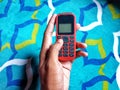 Hand Holding Old Mobile Phone with Texting or SMS Button Keyboard or Keypad on Colorful Carpet Background Royalty Free Stock Photo