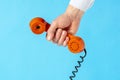 Hand holding old telephone receiver over blue background Royalty Free Stock Photo