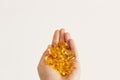 Hand holding omega 3 capsules on white wall background. Morning dose of vitamin. Fish oil in pills. Health support and treatment. Royalty Free Stock Photo