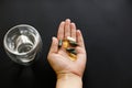 Hand holding omega 3, spirulina, chlorophyll,magnesium  capsules above glass of water. Morning dose of pills. Dietary supplements Royalty Free Stock Photo