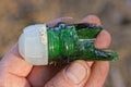 hand holding one old glass sharp green neck of a broken bottle with white plastic stopper on the street Royalty Free Stock Photo