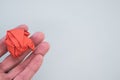 Hand holding an orange crumpled paper ball on a light green background Royalty Free Stock Photo