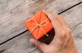 Hand Holding Orange Gift Box and Yellow Ribbon Royalty Free Stock Photo