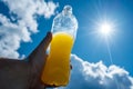Hand holding Orange lemonade towards sun and blue sky Royalty Free Stock Photo