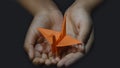 Hand holding Origami Paper Crane Orizuru, Orange bird.on Black Background Royalty Free Stock Photo