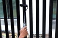 Hand holding paint roller applying black paint on the fence