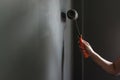 Hand holding paint roller applying grey paint on wall. Royalty Free Stock Photo
