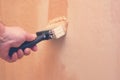 Hand holding paintbrush and repainting wall