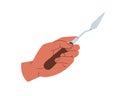 Hand holding painting knife for oil paint. Artists arm, wrist with painters trowel, steel tool with pointed blade for