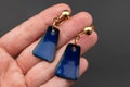 Hand holding a pair of blue earrings on a black background Royalty Free Stock Photo