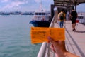 Hand holding pair of ferry tickets to St John`s Island against blur background of pier and sea Royalty Free Stock Photo