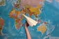 hand holding a paper airplane on the background of the world map.