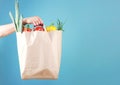 Hand holding paper bag with vegetables empty space blue background.Online market Royalty Free Stock Photo