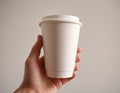 hand holding a paper cup of coffee on a gray background